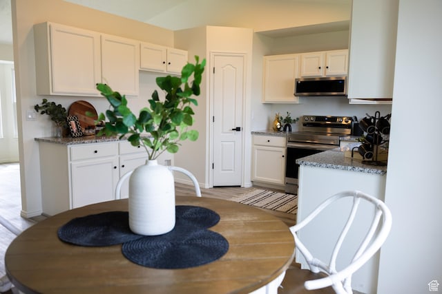 kitchen with stainless steel appliances, light wood-style floors, white cabinetry, and dark stone counters