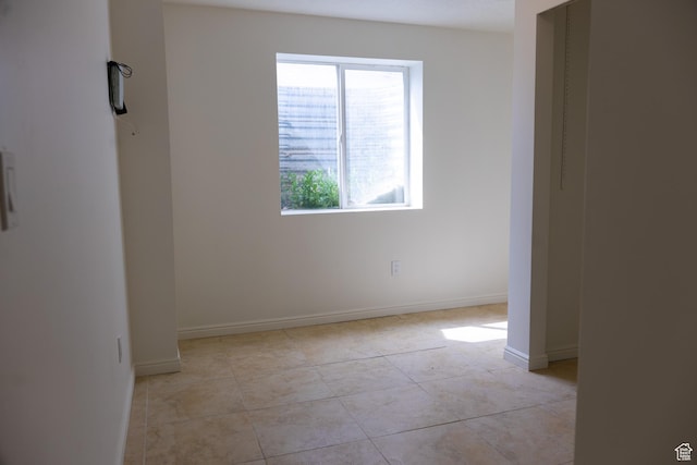 spare room with baseboards and light tile patterned flooring