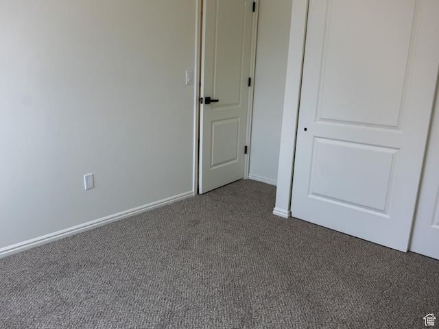 unfurnished bedroom featuring dark carpet and baseboards