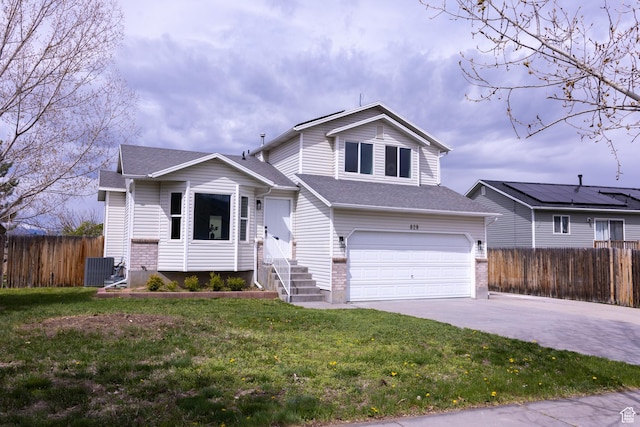tri-level home featuring a front yard, a shingled roof, an attached garage, fence, and driveway