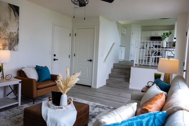 living area featuring ceiling fan, stairway, wood finished floors, and baseboards