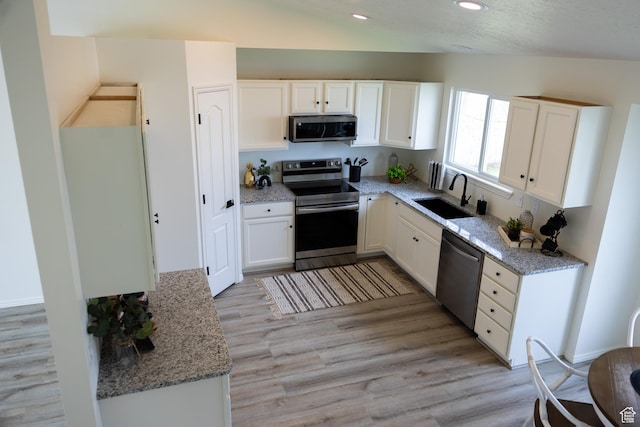 kitchen featuring a sink, appliances with stainless steel finishes, light stone counters, and white cabinetry