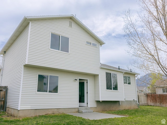 back of house with entry steps, a yard, and fence