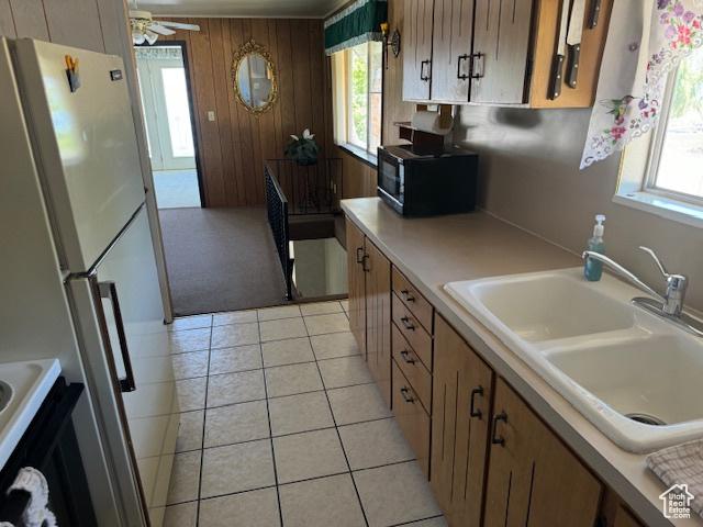1640 S Bear Lake Blvd, Garden City, UT 84028 - kitchen featuring freestanding refrigerator, black microwave, light countertops, light tile patterned floors, and brown cabinets
