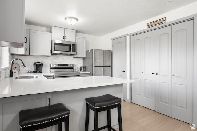 kitchen with tasteful backsplash, a breakfast bar, a peninsula, appliances with stainless steel finishes, and a sink