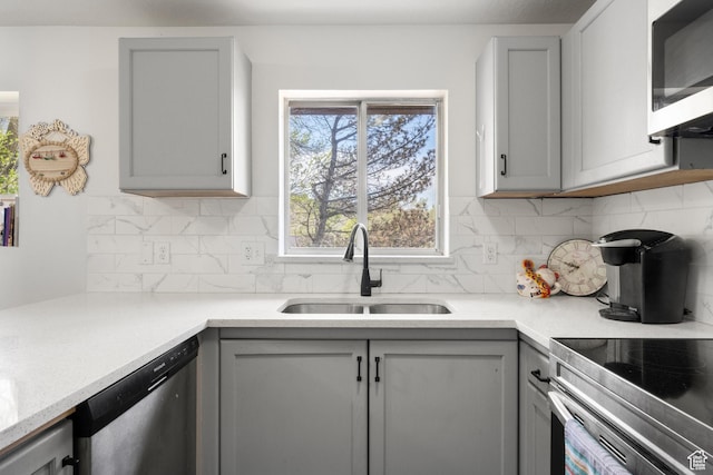 kitchen featuring a sink, gray cabinets, stainless steel dishwasher, and tasteful backsplash