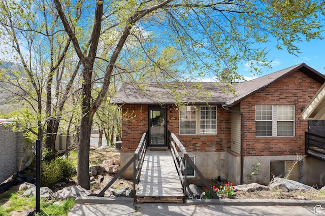 ranch-style house featuring a shingled roof, fence, and brick siding
