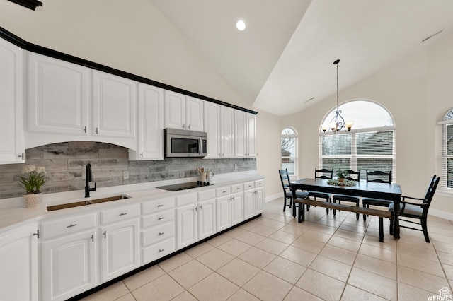 1141 S Waterside Dr, Saratoga Springs, UT 84045 - kitchen with stainless steel microwave, a chandelier, backsplash, black electric cooktop, and a sink