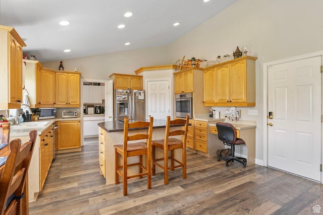 kitchen featuring a kitchen bar, a center island, appliances with stainless steel finishes, a sink, and lofted ceiling