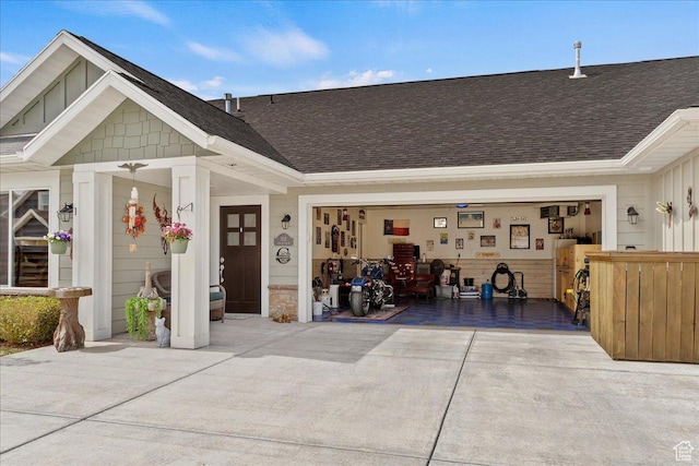 exterior space featuring roof with shingles, concrete driveway, a garage, and stone siding