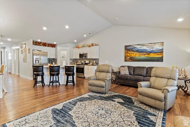 living room with recessed lighting, light wood-style floors, and vaulted ceiling