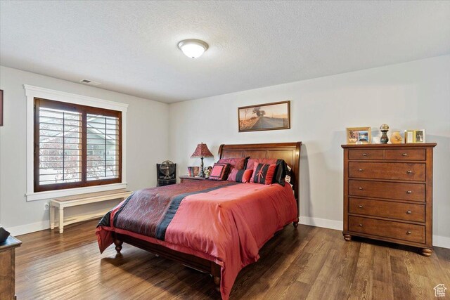 bedroom with visible vents, baseboards, and wood finished floors