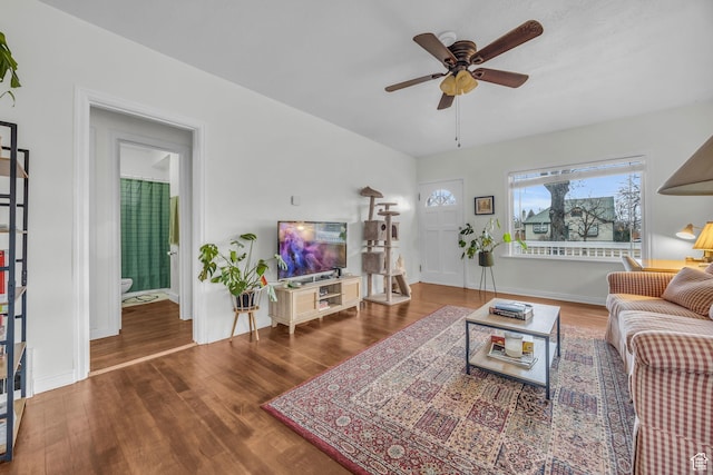 living area featuring wood finished floors, baseboards, and a ceiling fan