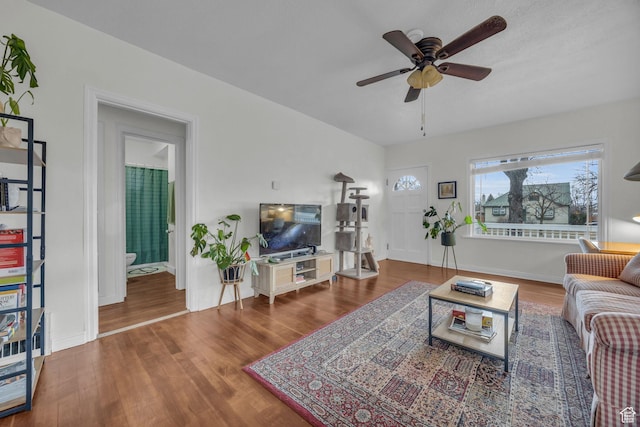 living area featuring baseboards, a ceiling fan, and wood finished floors