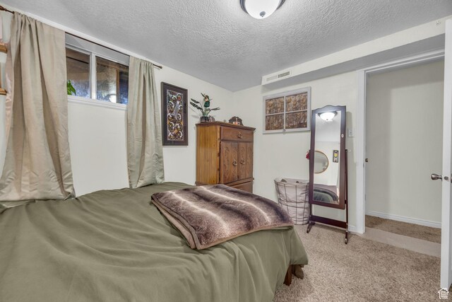 carpeted bedroom featuring a textured ceiling, baseboards, and visible vents