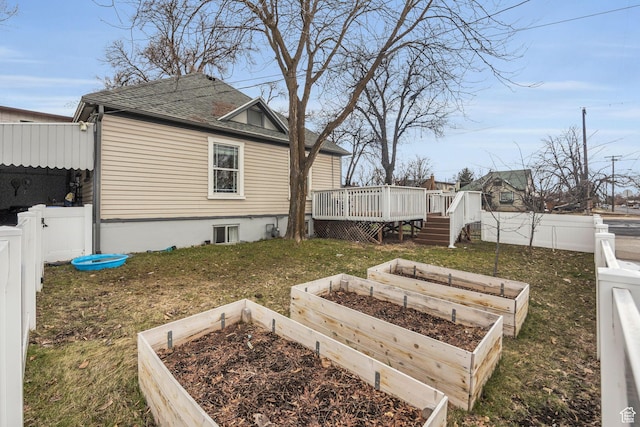view of yard featuring a garden, a fenced backyard, a deck, and a gate