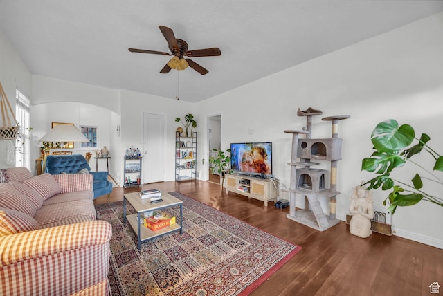 living room featuring arched walkways, wood finished floors, and a ceiling fan