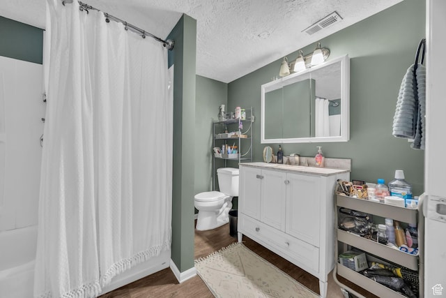full bathroom featuring visible vents, toilet, a textured ceiling, vanity, and wood finished floors