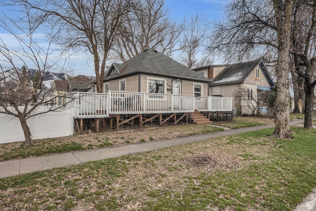 view of front facade featuring roof with shingles and a deck