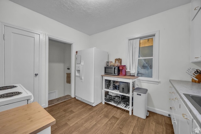 kitchen featuring white cabinets, white appliances, light wood-style flooring, and a textured ceiling