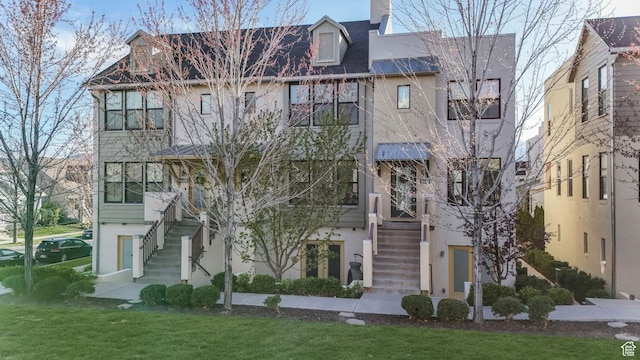 view of front of home with stairs and a front lawn