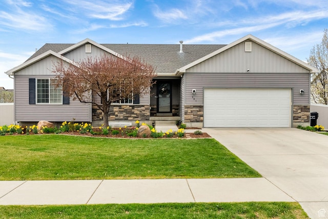 view of front of house with concrete driveway, stone siding, a front lawn, a garage, and a shingled roof
