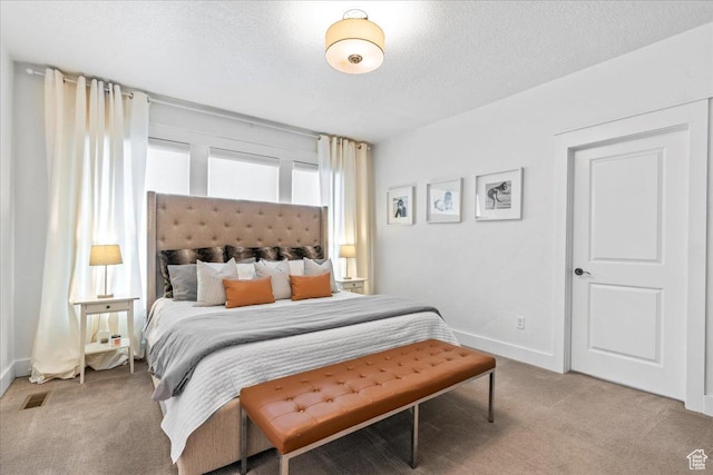 bedroom with light carpet, baseboards, and a textured ceiling
