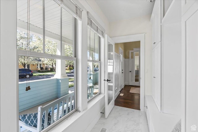 corridor featuring marble finish floor and a healthy amount of sunlight