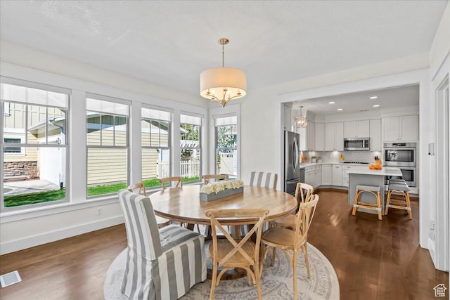 dining area with dark wood-type flooring, visible vents, baseboards, and a chandelier