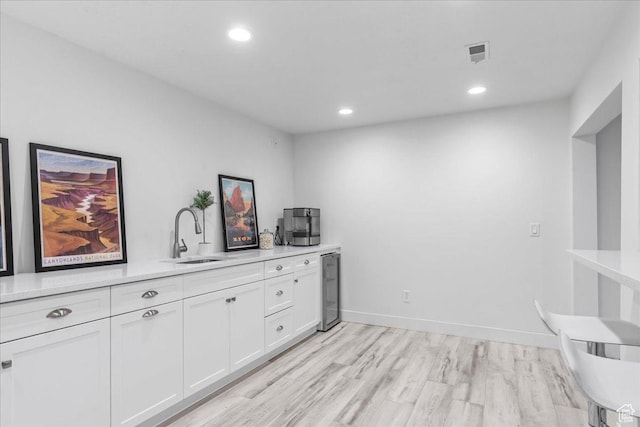 interior space featuring visible vents, a sink, light wood-style floors, wine cooler, and recessed lighting