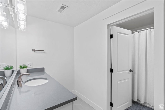 bathroom with tile patterned floors, vanity, visible vents, and a textured ceiling