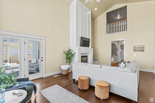 living room with high vaulted ceiling, a fireplace, dark wood-style flooring, and baseboards