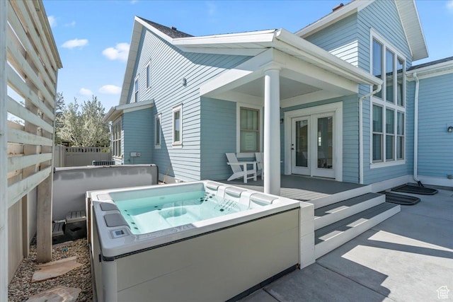 rear view of house with french doors, fence, and a hot tub