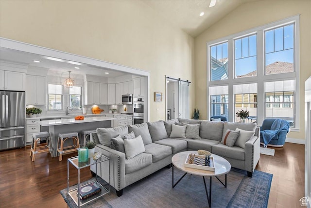 living room featuring dark wood-style flooring, high vaulted ceiling, recessed lighting, and a barn door