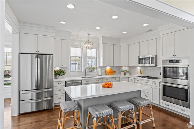 kitchen with light countertops, a sink, a kitchen bar, and appliances with stainless steel finishes