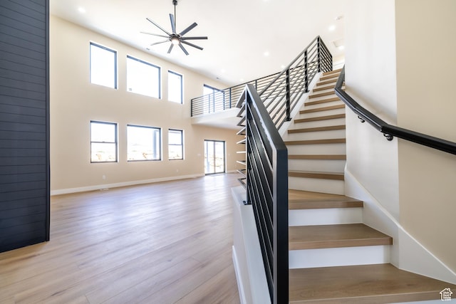 2899 E Lake Dr, Eagle Mountain, UT 84005 - stairway featuring wood finished floors, a towering ceiling, baseboards, and recessed lighting