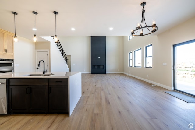 2899 E Lake Dr, Eagle Mountain, UT 84005 - kitchen featuring light countertops, light wood-style floors, a fireplace, and a sink
