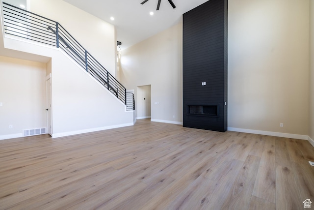 2899 E Lake Dr, Eagle Mountain, UT 84005 - unfurnished living room with ceiling fan, visible vents, a high ceiling, stairs, and light wood finished floors