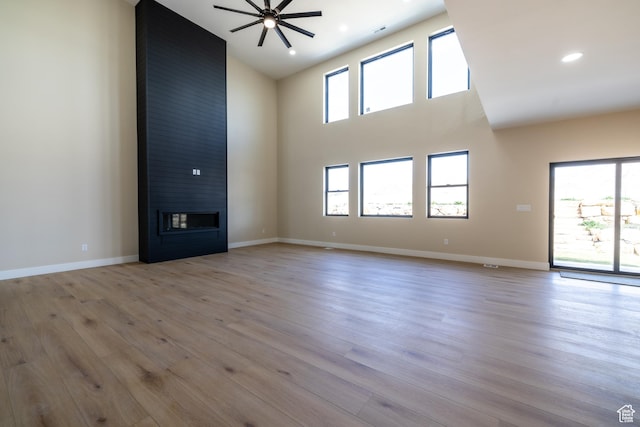 2899 E Lake Dr, Eagle Mountain, UT 84005 - unfurnished living room with baseboards, a fireplace, a high ceiling, ceiling fan, and light wood finished floors