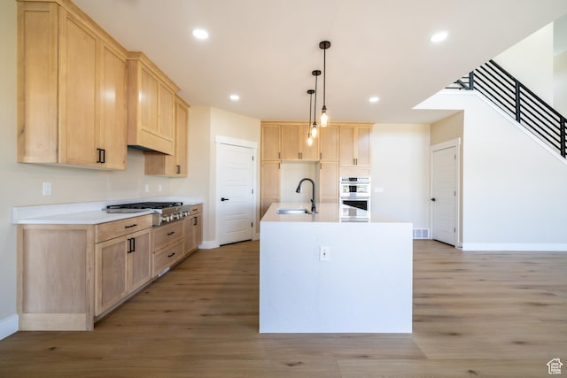 2899 E Lake Dr, Eagle Mountain, UT 84005 - kitchen with baseboards, a sink, light brown cabinetry, light wood-style flooring, and stainless steel gas cooktop