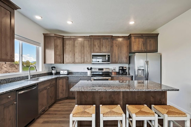 2250 S Beachcomber Ln, Garden City, UT 84028 - kitchen with dark wood-style flooring, a breakfast bar, dark stone counters, appliances with stainless steel finishes, and a sink