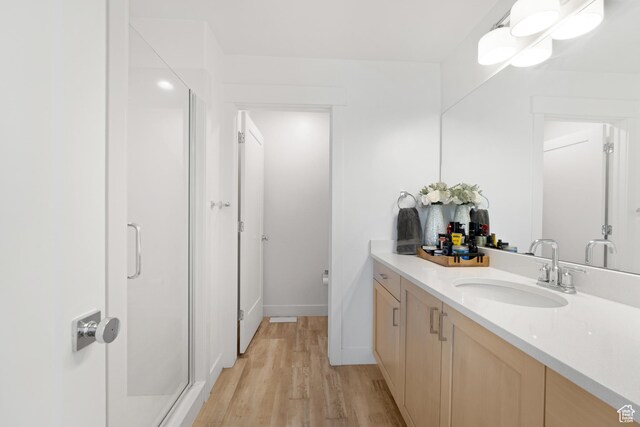 full bath featuring a stall shower, wood finished floors, vanity, and baseboards