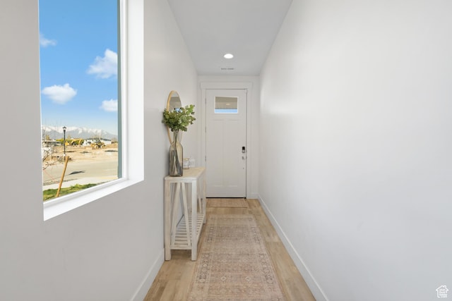 hallway with light wood-style floors, baseboards, a mountain view, and recessed lighting