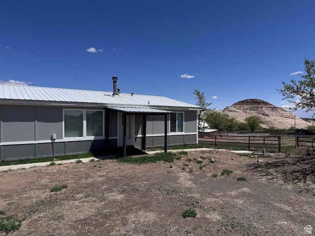 back of house featuring fence and metal roof