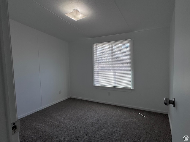 empty room featuring dark carpet and baseboards