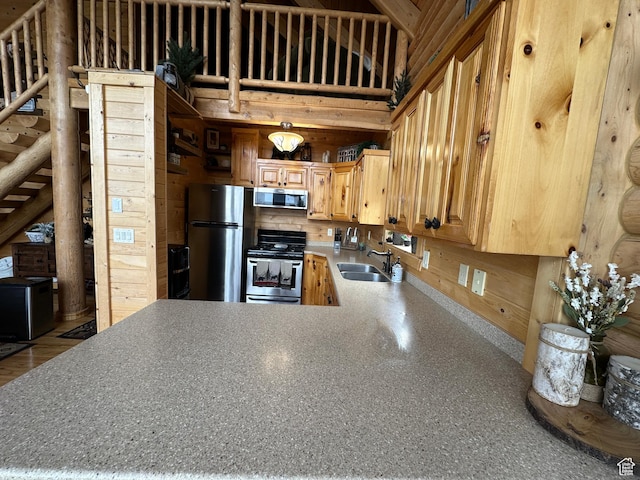 1741 S Red Canyon Dr, Parowan, UT 84761 - kitchen with a peninsula, light brown cabinetry, appliances with stainless steel finishes, wood walls, and a sink