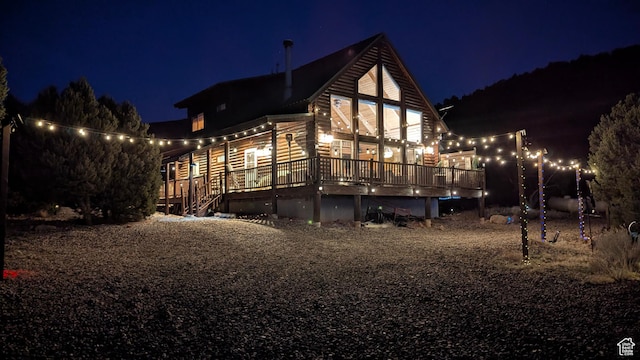 property exterior at night featuring a wooden deck