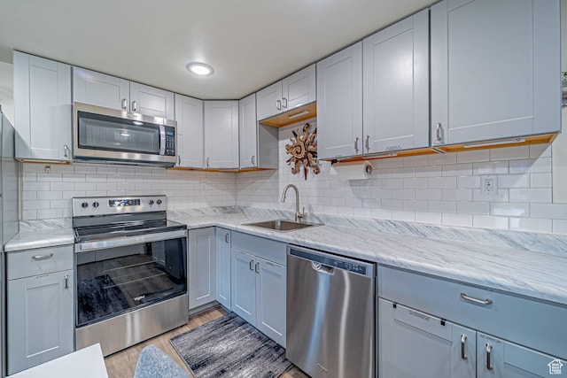 524 Westwood Ave, Moab, UT 84532 - kitchen featuring appliances with stainless steel finishes, light stone countertops, light wood-style flooring, and tasteful backsplash