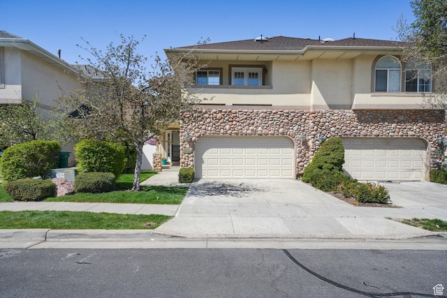 townhome / multi-family property featuring a garage, stucco siding, stone siding, a balcony, and concrete driveway