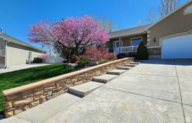 6723 W Hunter Farm Cir S, West Valley City, UT 84128 - view of front facade with stucco siding, concrete driveway, an attached garage, covered porch, and fence